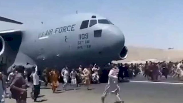 Warga mengejar dan berpegangan pada pesawat militer Amerika Serikat (AS) yang bergerak meninggalkan bandara Kabul, Afghanistan, Senin 16 Agustus 2021 (Foto: Int)