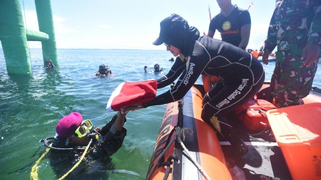 Bupati Luwu Utara Indah Putri Indriani bersama Persatuan Olahraga Selam Seluruh Indonesia (POSSI) Luwu Utara mengibarkan bendera merah putih dari dasar laut perairan Teluk Bone, Desa Munte, Kecamatan Tanalili, Kabupaten Luwu Utara, pada Selasa (16/8/2022). 