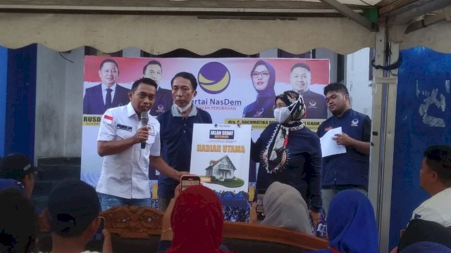 Sekretaris DPW NasDem Sulsel, Syaharuddin Alrif menyerahkan hadiah secara simbolis kepada pemenang undian hadiah rumah tinggal. 