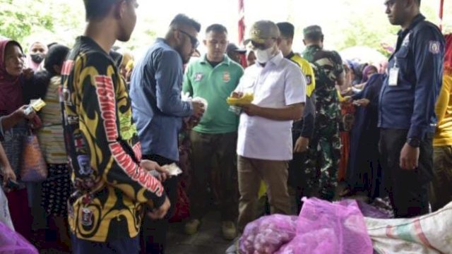 Penjabat Gubernur Gorontalo, Hamka Hendra Noer saat turun langsung melayani masyarakat yang membeli bahan pokok rempah-rempah di pasar murah yang berlokasi di Lapangan Taruna Remaja, Kota Gorontalo, Minggu (6/11/2022).