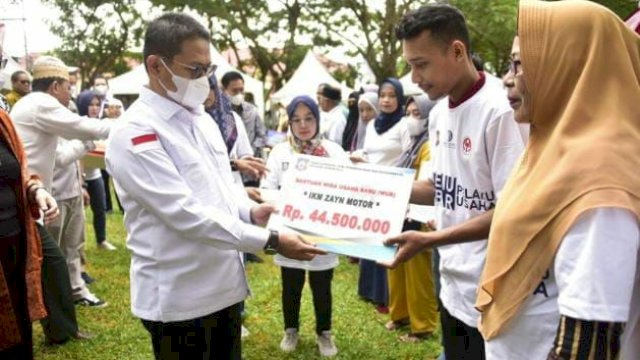 Penjagub Hamka Hendra Noer saat menyerahkan secara simbolis bantuan kepada pelaku IKM Provinsi Gorontalo, melalui kegiatan Temu Akbar Pelaku Usaha yang digelar di halaman kantor Dinas Koperasi, UMKM, Perindustrian dan Perdagangan (Diskumperindag), Jumat (18/11/2022).