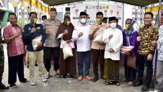 Penjagub Hamka didampingi Bupati Kabupaten Gorontalo Nelson Pomalingo saat menyerahkan beras kepada masyarakat usai melakukan vaksin, pada penyelenggaraan vaksinasi massal yang digagas oleh Pemda Kabgor, di Halaman Masjid Baiturrahman Limboto, Jumat (2/12/2022).