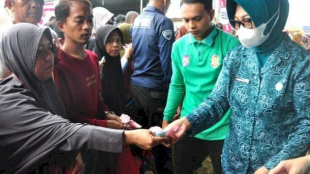 Ketua TP. PKK Provinsi Gorontalo, Gamaria Purnamawari Monoarfa (kanan), turut melayani warga yang berbelanja pada pasar murah di lapangan Kelurahan Padebuolo, Kecamatan Kota Timur, Kota Gorontalo, Minggu (4/12/2022).