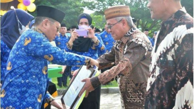 Penjagub Gorontalo, Hamka Hendra Noer (kiri), menyerahkan santunan dari Dewan Pengurus Korpri kepada ASN yang telah memasuki masa pensiun pada upacara memperingati HUT ke-22 Provinsi Gorontalo yang dirangkaikan dengan HUT ke-51 Korpri di lapangan Museum Purbakala Popa Eyato, Senin (5/12/2022).