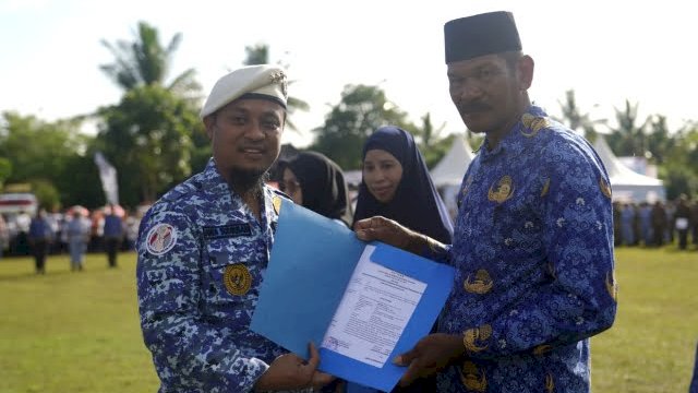 Gubernur Sulawesi Selatan, Andi Sudirman Sulaiman saat menyerahkan SK ke salah satu PPPK jabatan fungsional guru tahap II Formasi Tahun Anggaran 2021 di Lapangan Latemmupage, Desa Bulue, Kabupaten Soppeng, Senin, (19/12/2022).