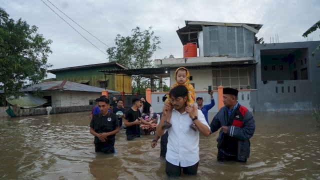 Ketua Forum Kemanusiaan Kota Makassar (FKKM), dr. Udin Malik saat mengevakuasi ibu dan balita warga terdampak banjir di Jalan Perintis Kemerdekaan IV, Tamalanrea, Jumat (17/2/2023).