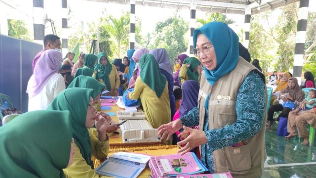 Ketua TP-PKK Provinsi Gorontalo drg. Gamaria Monoarfa saat berbincang dengan petugas dari Dinas Kesehatan Provinsi Gorontalo saat pemeriksaan buku KIA pada pelaksanaan skrining untuk pengukuran berat badan dan tinggi badan anak balita, Desa Daenaa, Kecamatan Limboto Barat, Kabupaten Gorontalo, Kamis (16/03/23). 