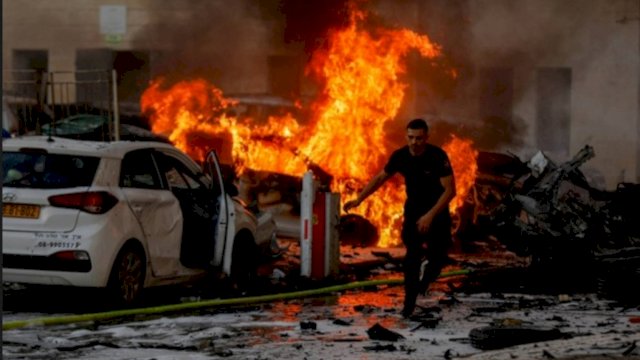 Seorang pria berlari di jalan saat api berkobar setelah roket diluncurkan dari Jalur Gaza, di Ashkelon, Israel, Sabtu (7/10/2023). (Foto: REUTERS) 