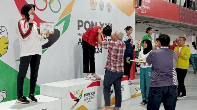 Pj. Gubernur Gorontalo, Rudy Salahuddin, mengalungkan medali emas kepada atlet Silvana Lamanda, di GOR Martial Arts Arena, Medan, Kamis (12/9/2024).