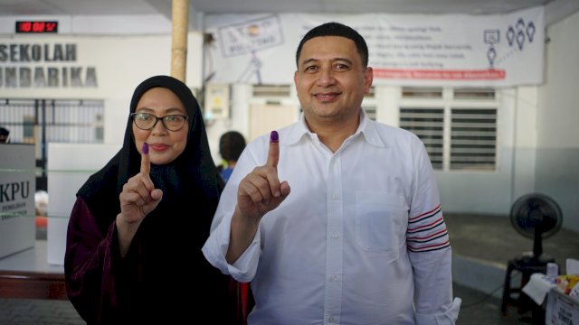 Calon Wali Kota Makassar nomor urut 1, Munafri Arifuddin (kanan) didampingi istrinya, Melinda Aksa menyalurkan gak pilihnya di TPS 02 Kelurahan Sawerigading sekira pukul 08.50 Wita, Rabu (27/11/2024). 