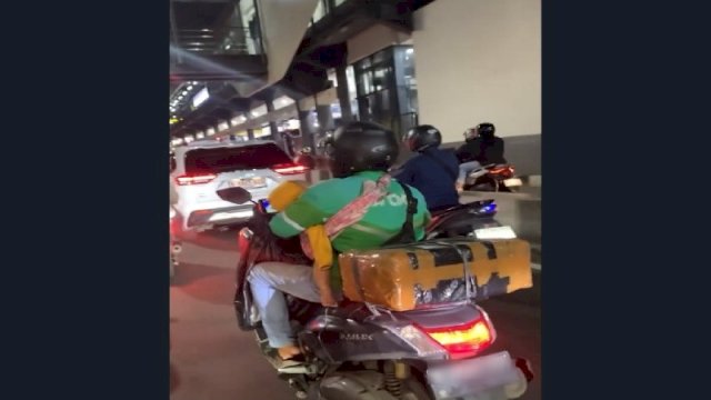 Aksi driver ojol menggendong anak sembari mengantarkan paket pelanggan. (Foto: TikTok @quetiawww)